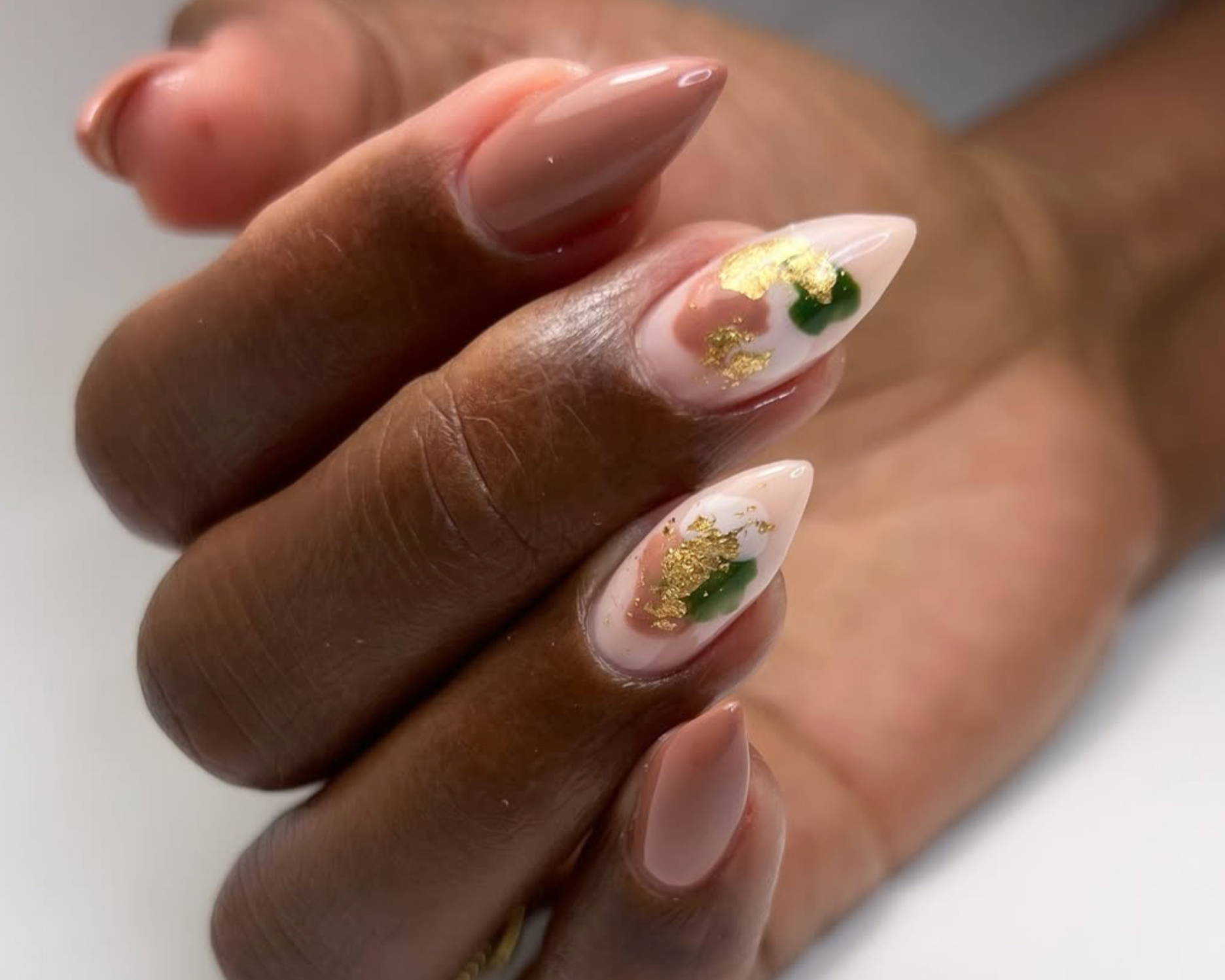 stiletto shaped nails with gold and green accents